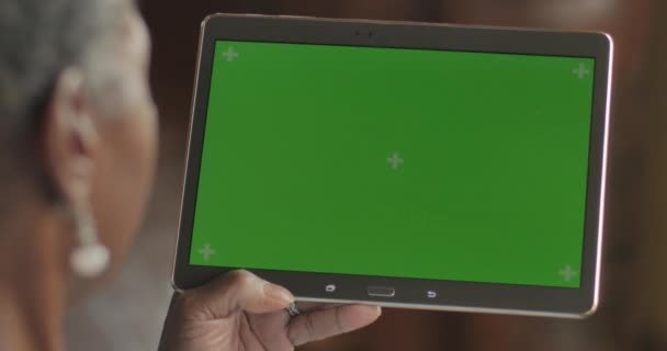 Senior black woman swiping and tapping a green screen digital tablet - OTS - Felvétel, videó