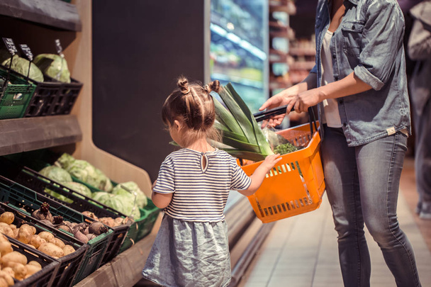 Mom and daughter are shopping at the supermarket, the concept of family relationships and healthy eating - Foto, Imagen