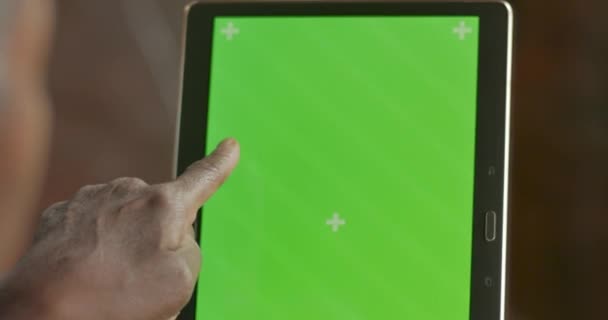 Black woman's hand swiping, touching, and tapping a green screen tablet screen - Video