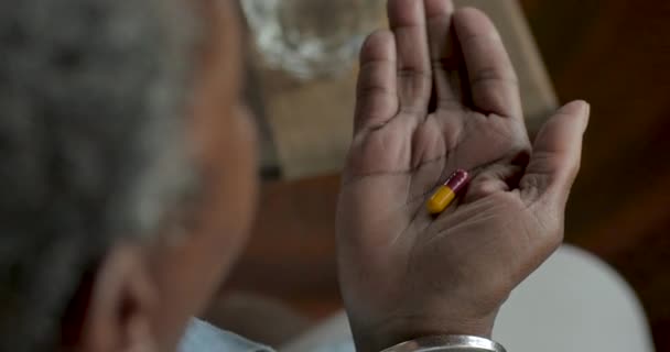 Idős fekete nő, figyelembe véve a gyógyszeripari kábítószer kapszula otthonában - Felvétel, videó