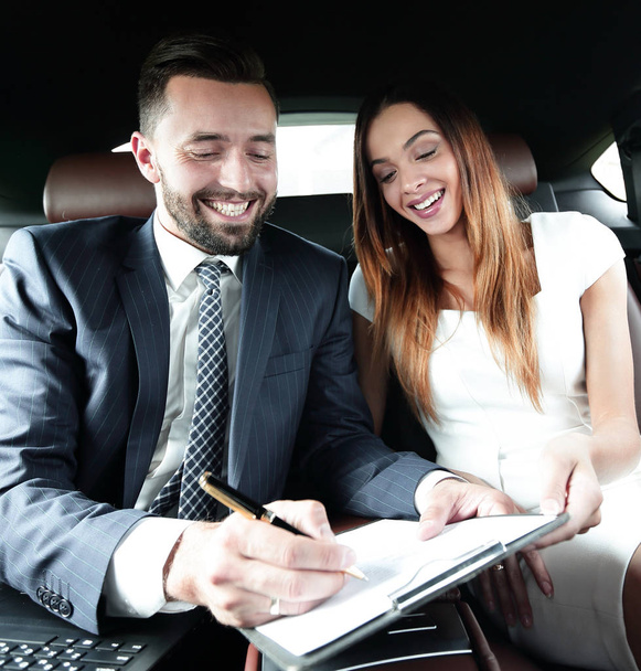 Beautiful business woman working with a client in the car - Foto, Bild