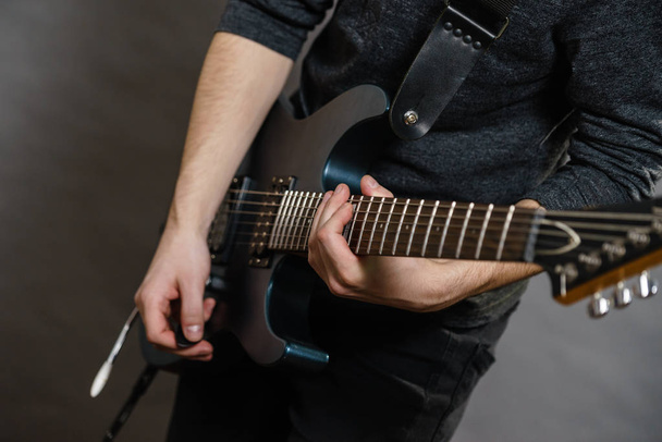 Male hands with electric guitar. Close up, part body adult person is holding instrument and playing. Hobby, music concept - Foto, afbeelding