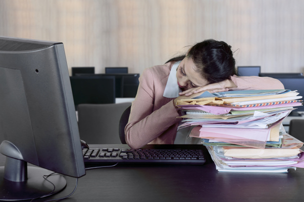 Imprenditrice donna che dorme sopra mucchio di documenti mentre lavora con il computer. Girato in ufficio
 - Foto, immagini