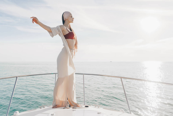 a luxurious stylish girl in summer clothes enjoying a warm summer wind on a yacht, a long-awaited vacation - Photo, Image