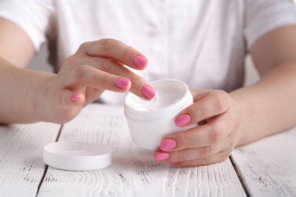 Closeup shot of hands applying moisturizer. Beauty woman holding a glass jar of skin cream - Фото, изображение