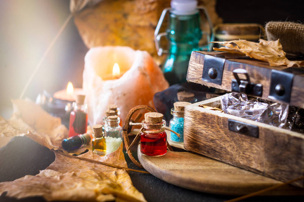 Magic concept. Potions in bottles, candles, box and orange leaves. Magical background - Φωτογραφία, εικόνα