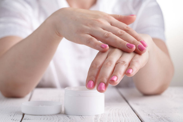 Closeup shot of hands applying moisturizer. Beauty woman holding a glass jar of skin cream - Фото, зображення