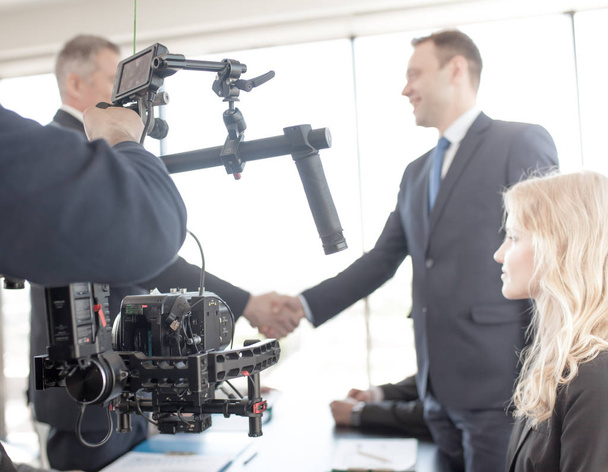 Videographer using steadycam, making video of business people shaking hands - Photo, image