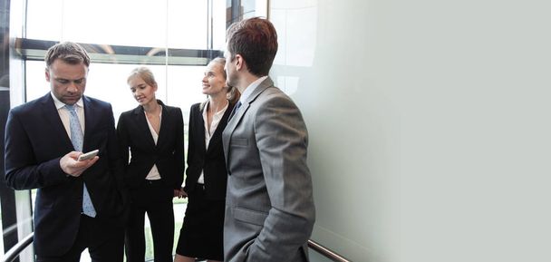 Business team group going on elevator. Business people in a large glass elevator in a modern office - Фото, изображение