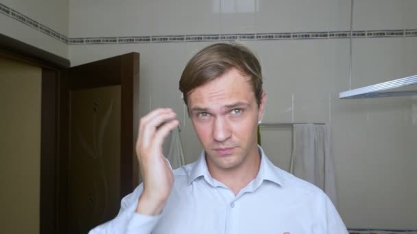 Молодий привабливою чоловік оглядає відступаючою лінії росту волосся у ванній кімнаті. Облисіння - Кадри, відео