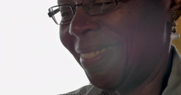 Happy elderly black woman using her mobile phone at home - tilt down close up - Metraje, vídeo