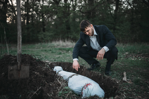 Маньяк против могилы, окровавленная жертва завернутая в холст, концепция серийного убийцы, ночной ужас преступления, насилие
 - Фото, изображение