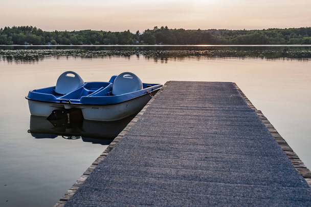 Fila de lanchas de pedal azul durante una puesta de sol en un lago americano
 - Foto, imagen