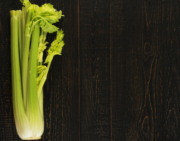Na pozadí pohledu shora nebo syrové zelené řapíkatý celer. Čerstvá biozelenina na starý dřevěný rustikální stůl s místem pro text nebo copyspace - Fotografie, Obrázek
