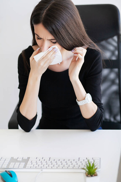 Dolor. Enferma mujer de negocios que sufre en el trabajo detrás del escritorio en su oficina y tiene un problema de alergia
. - Foto, imagen