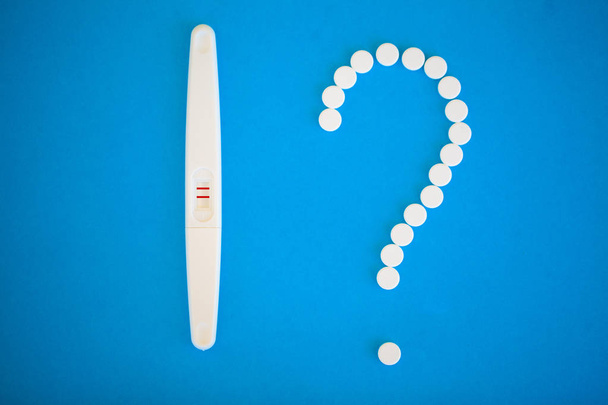 O resultado é positivo. Close-up de teste de gravidez e pílulas contraceptivas conceito de controle de natalidade em fundo azul
. - Foto, Imagem