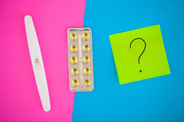 Test di gravidanza. Il risultato è positivo con due strisce e preservativo con contraccettivo su sfondo colorato, pillola anticoncezionale, sesso sicuro, assistenza sanitaria concep
. - Foto, immagini