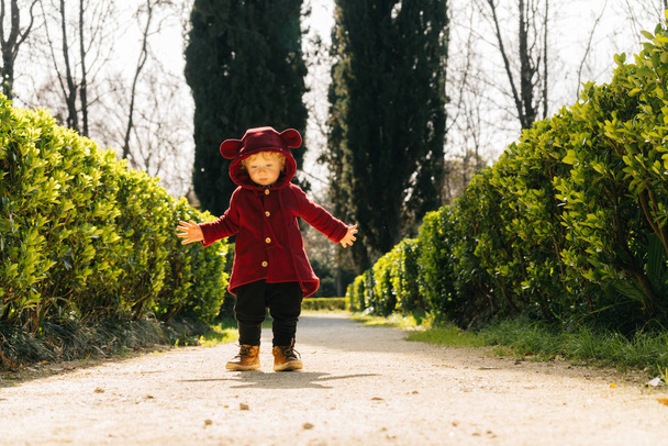 un piccolo bambino biondo in un bel vestito passeggia per il parco al sole
 - Foto, immagini