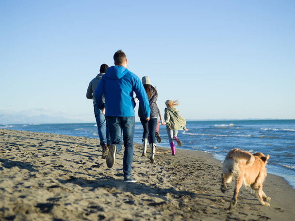 group of young friends spending day together running on the beach during autumn day - 写真・画像