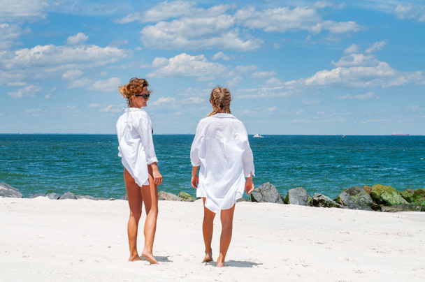 Boldogságot a pillanatban. Két vonzó nő a bikini a strandon. A legjobb barátok, séta a tengerparton, nyaralás.  - Fotó, kép