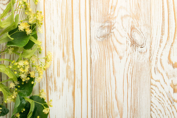 Линден Флауэрс на деревянном фоне. Летний букет над текстурой деревянного стола. Тилия Блоссом с местом для текста
 - Фото, изображение