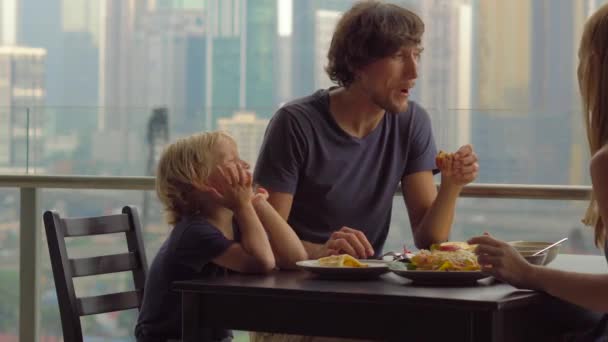 Jeune famille prenant un petit déjeuner, déjeuner sur leur balcon dans un gratte-ciel avec vue sur tout un centre ville
 - Séquence, vidéo