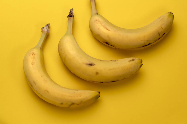 Τρία φρούτα μπανάνα που απομονώνονται σε κίτρινο φόντο - Φωτογραφία, εικόνα