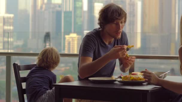 Familia joven desayunando, almorzando en su balcón en un rascacielos con vistas a todo el centro de la ciudad
 - Imágenes, Vídeo