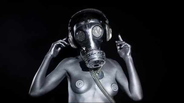 Mujer sexy bailando en pintura de cuerpo plateado y máscara de gas sobre fondo negro
 - Metraje, vídeo