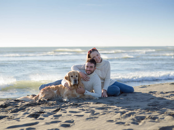 Couple With A Dog enjoying time  together On The Beach at autumn day - Foto, Bild
