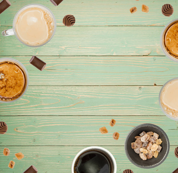 kreatives Essensmuster mit Kaffeetassen auf türkisfarbenem Holzhintergrund von oben. Heißgetränke-Layout mit Copyspace - Foto, Bild