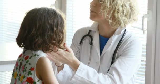 woman in white coat is a doctor checking her little patient in her clinic and everything goes well - Кадри, відео