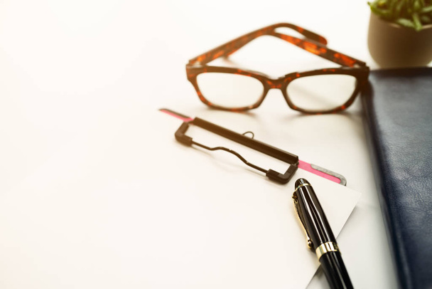 ручка и буфер обмена с чистым листом, очки на дневнике книги на белом фоне с копировальным пространством
 - Фото, изображение