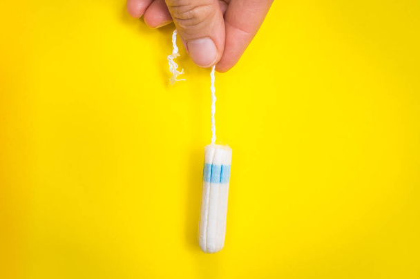 Nő menstruáció tampon tartja a kezében a sárga háttér - menstruációs higiénia fogalma - Fotó, kép