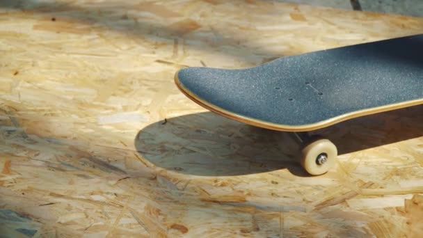 Skateboard mit weißen Rädern auf einem hölzernen Hintergrund in einem Skatepark - Filmmaterial, Video