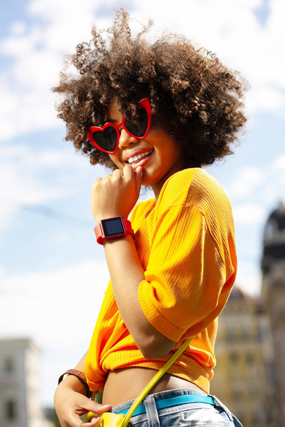 Upbeat curly woman wearing heart-shaped sunglasses - Foto, Imagem