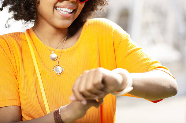 Close up of cheerful curly woman checking watch - Photo, Image