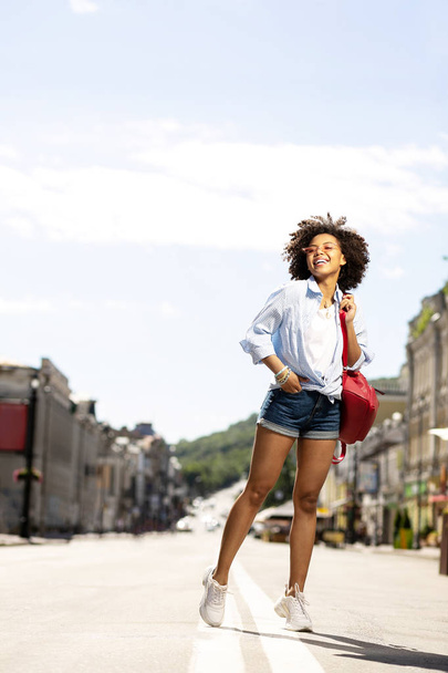 Cheerful curly woman having tour in new city - 写真・画像