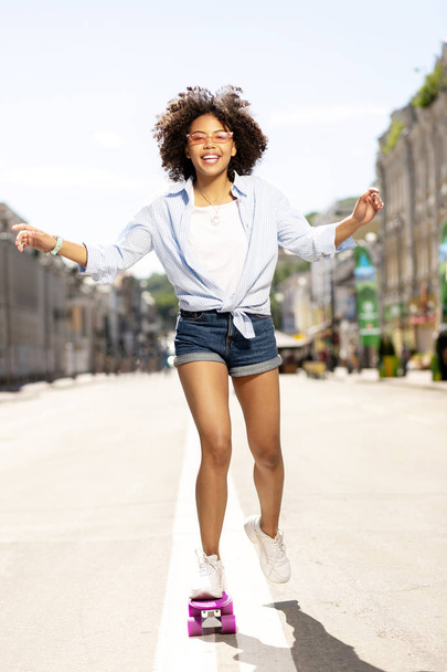 Upbeat young woman riding mini skateboard - Фото, изображение