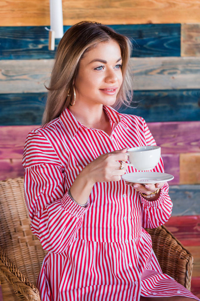 Beautiful blonde woman drinking coffee or tea in the morning and smiling. Lifestyle, happiness, life concept - Fotó, kép