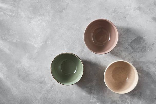 three colorful porcelain handmade pottery bowls on stone gray background  - Foto, immagini