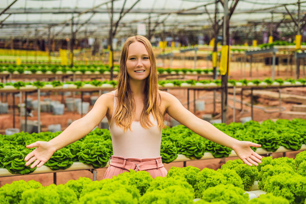 Young female farmer researching plants in hydroponic salad farm. Agriculture and scientist concept. - Foto, afbeelding
