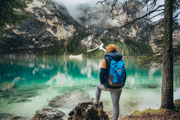 Chłopiec wychodzi na jezioro lustro, w górach, w kurtkę brązowy i niebieski plecak - Zdjęcie, obraz