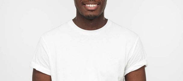 Close up portrait of smiling handsome african american man in blank white t-shirt isolated on light gray background - Fotoğraf, Görsel
