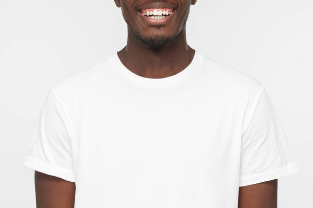 Detailní záběr ať se usmívám americký krasavec v prázdné bílé tričko izolované na světle šedém pozadí - Fotografie, Obrázek