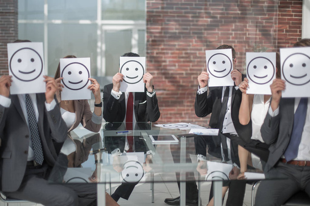 business team keeps smiley icons sitting at the Desk - Fotoğraf, Görsel