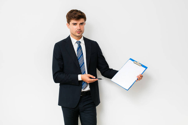 confident businessman in suit showing his clipboard to camera and smiling, standing on white background - Foto, immagini