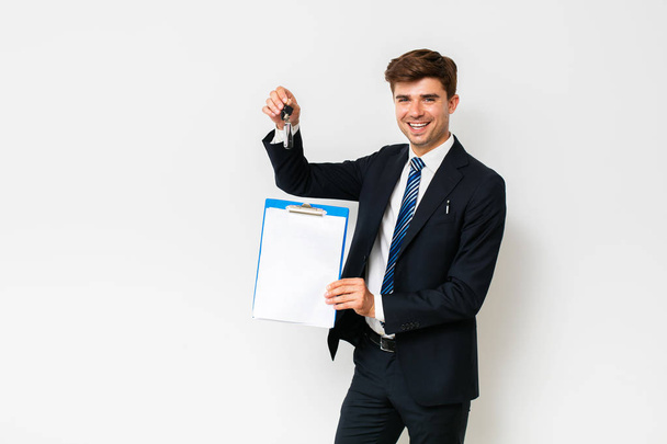 time for new car. elegant salesman, closing a deal and selling a car to a new client, standing on white with car keys and clipboard with contract - Zdjęcie, obraz
