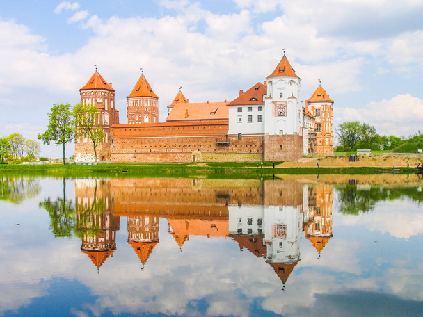 Mir, Wit-Rusland. Kasteel complexe Mir weerspiegeld in lake op zonnige dag met blauwe hemel achtergrond. Oude middeleeuwse torens en muren van traditionele fort uit de unesco-werelderfgoedlijst - Foto, afbeelding