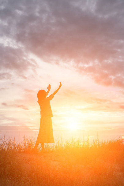 Silhouette einer betenden Frau über schönen Himmelshintergrund - Foto, Bild